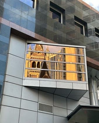 An ornate heritage facade reflected in the window of a modern grey-clad building